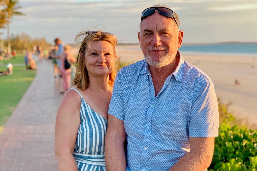 A couple with the beach in the background at sunset
