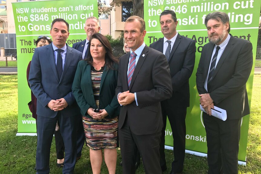 A group, including NSW MPs, stand in front of two sings advocating for education spending.