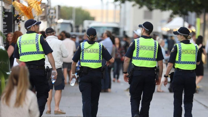 Four police officers walk in a row, their faces are not visible.