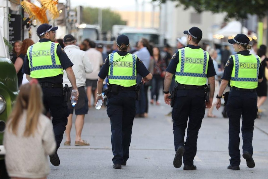 Four police officers walk in a row, their faces are not visible.