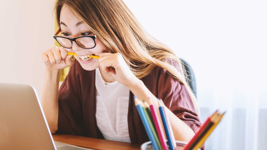 A stressed woman bites a pencil