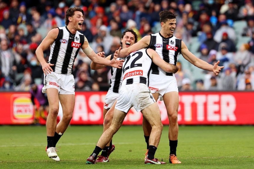 Scott Pendlebury smiles as Magpies players get around him to celebrate