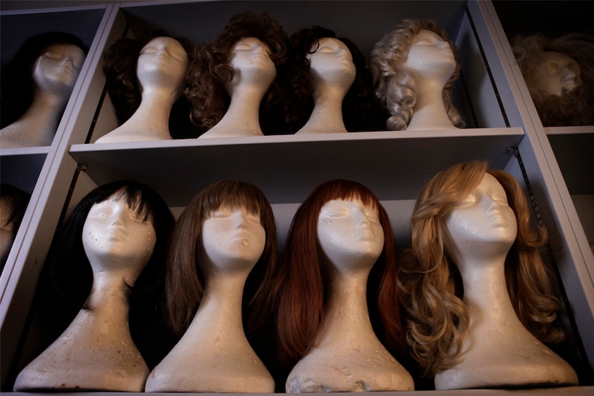 Shelves full of mannequin heads wearing wigs of various styles in the ABC's props room.