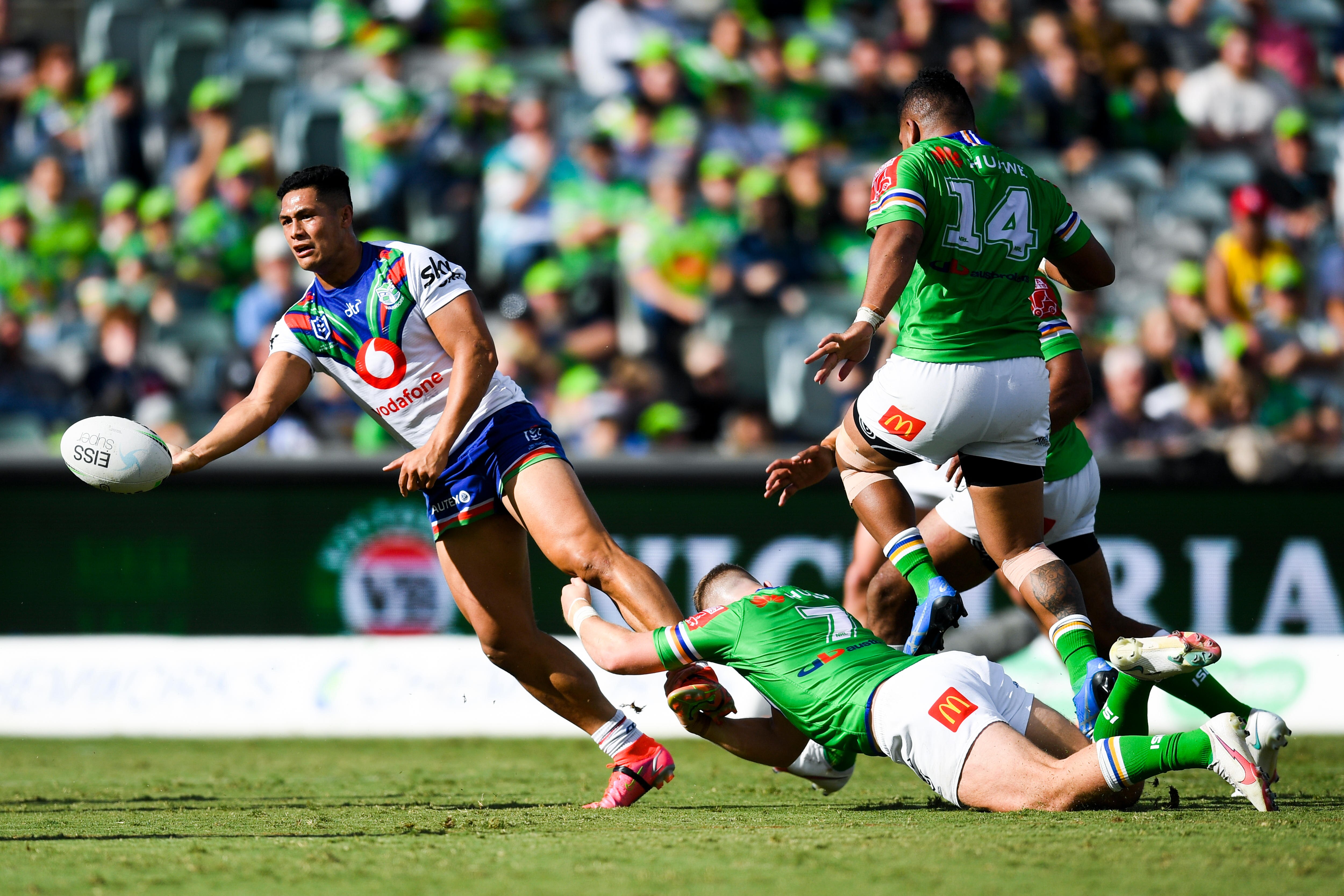 Rugby league players running the ball with opposing players trying to tackle him  