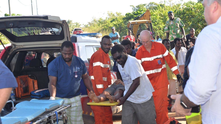 Crowds gather as emergency workers carry people on stretchers