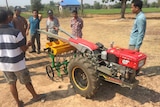 Farmers look at a new rice seeder.