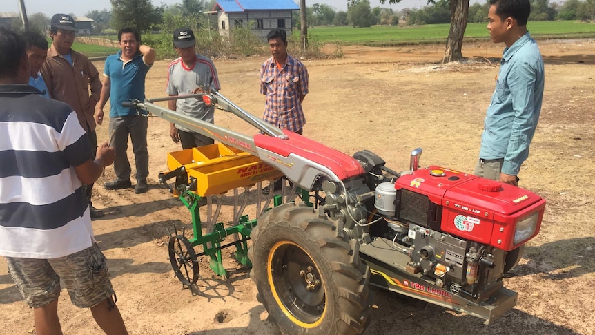 Farmers look at a new rice seeder.