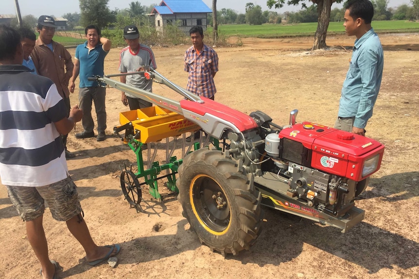 Farmers look at a new rice seeder.