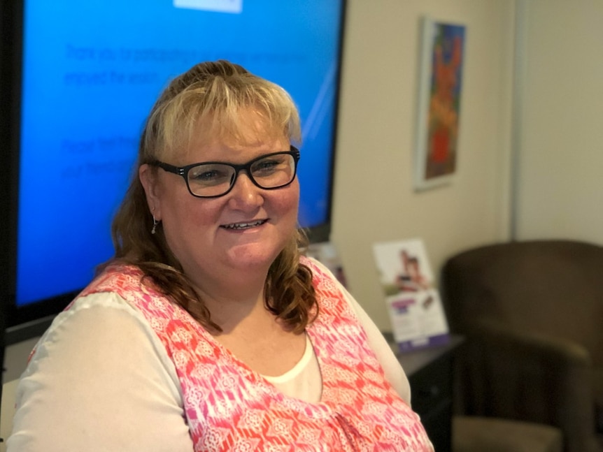 Woman standing in front of a projector screen smiling.