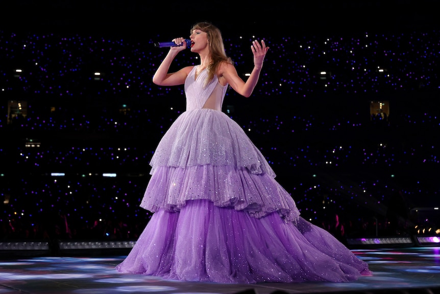 Taylor Swift performs in a glittering lavender ballgown.