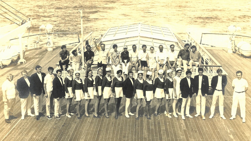 A black and white photo of a uniformed crew on deck a cruise ship