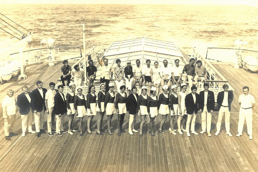 A black and white photo of a uniformed crew on deck a cruise ship
