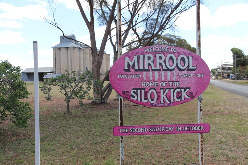 A pink sign shaped like an Aussie Rules football that says "Welcome to Mirrool; home to the silo kick".