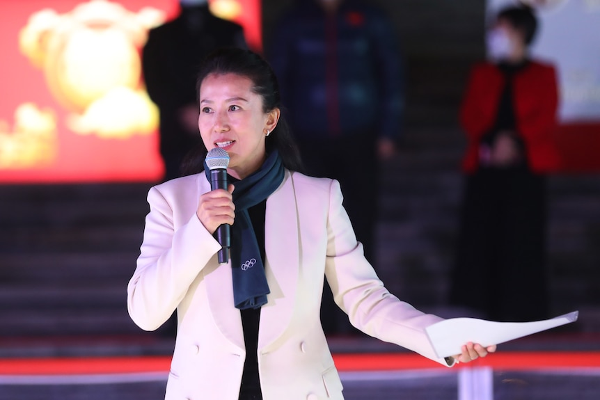 Woman holds a microphone as she presents during an outdoor event. 