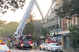 A fire truck with a long ladder and basket approaches a building