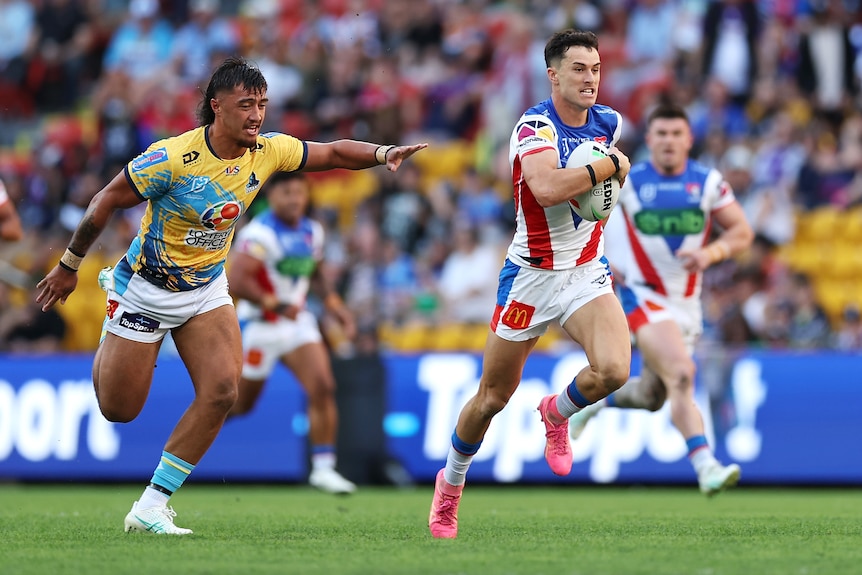 David Armstrong of the Newcastle Knights runs away from Gold Coast Titans' Klese Haas.