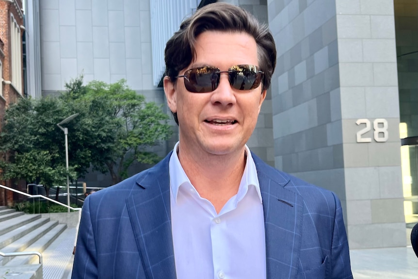 Foto de cabeza de un hombre con gafas de sol con un edificio de la ciudad al fondo