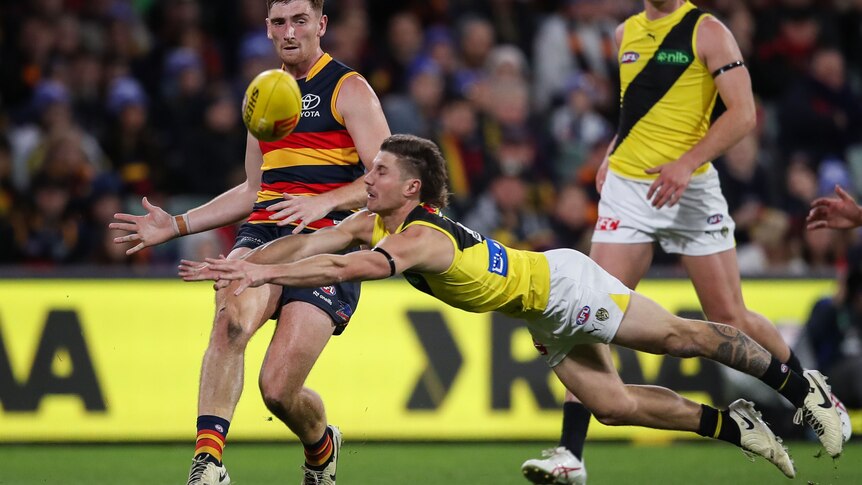 A footballer attempts to smother during an AFL match