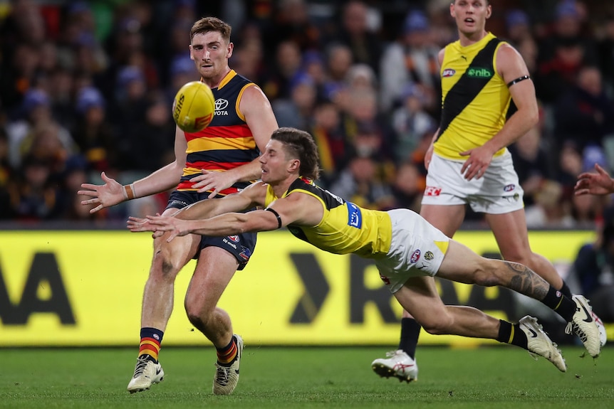 A footballer attempts to smother during an AFL match
