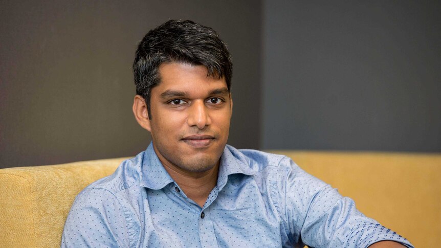 A young man sits on a couch.