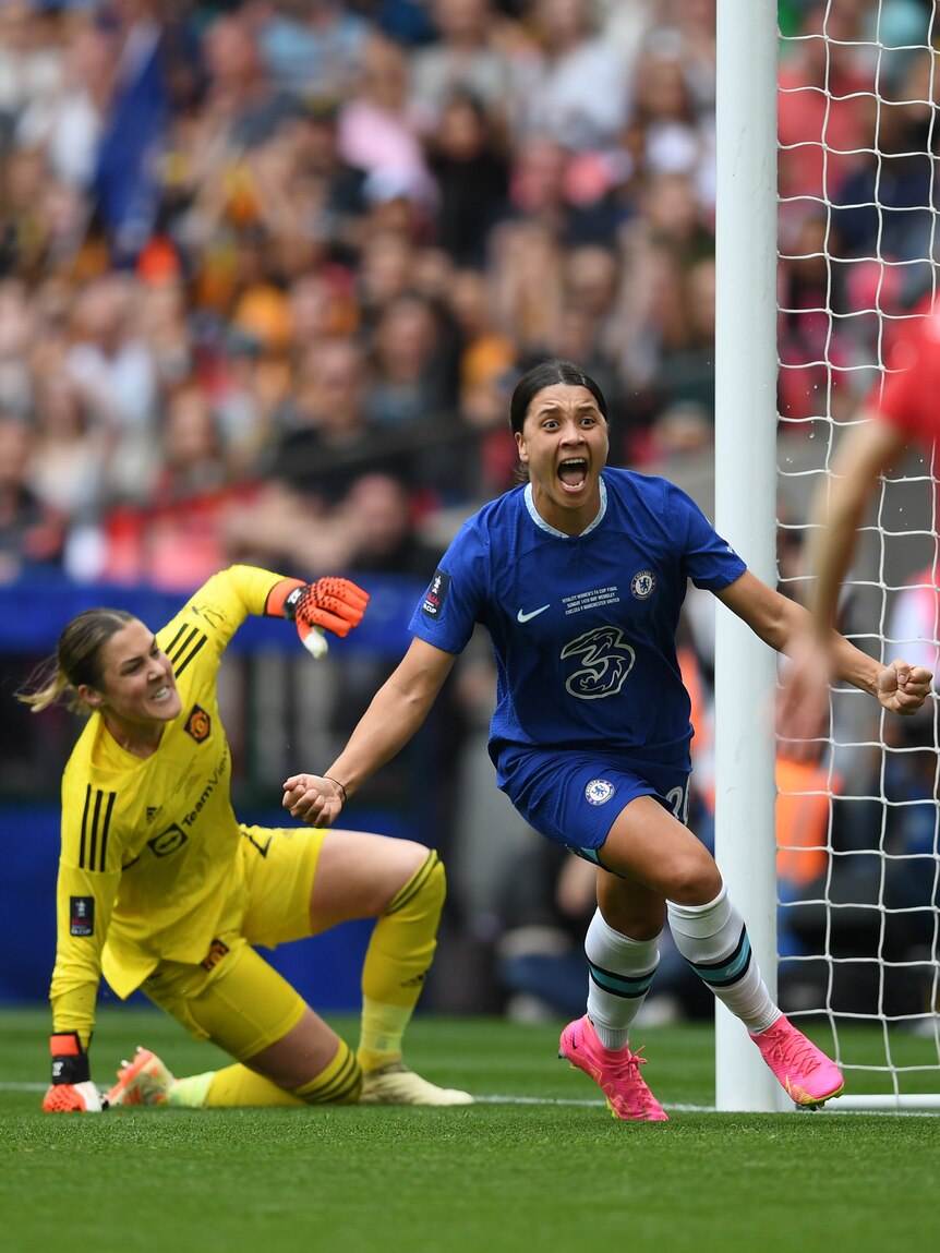 A soccer player wearing blue runs off screaming as a goalkeeper in yellow scrambles behind her during a game.