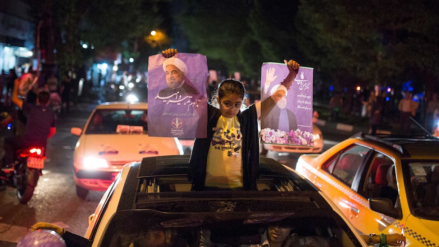 A girl holds posters of Iranian President Hassan Rouhani.