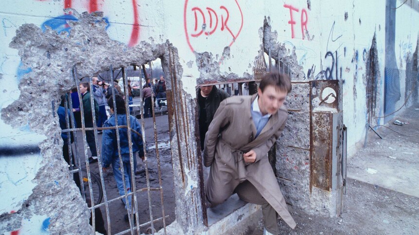 A man walks through a small door in the Berlin Wall in 1989, after the borders were opened.
