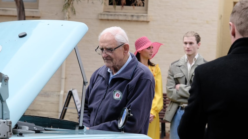 Man looks in vintage blue vehicle hood