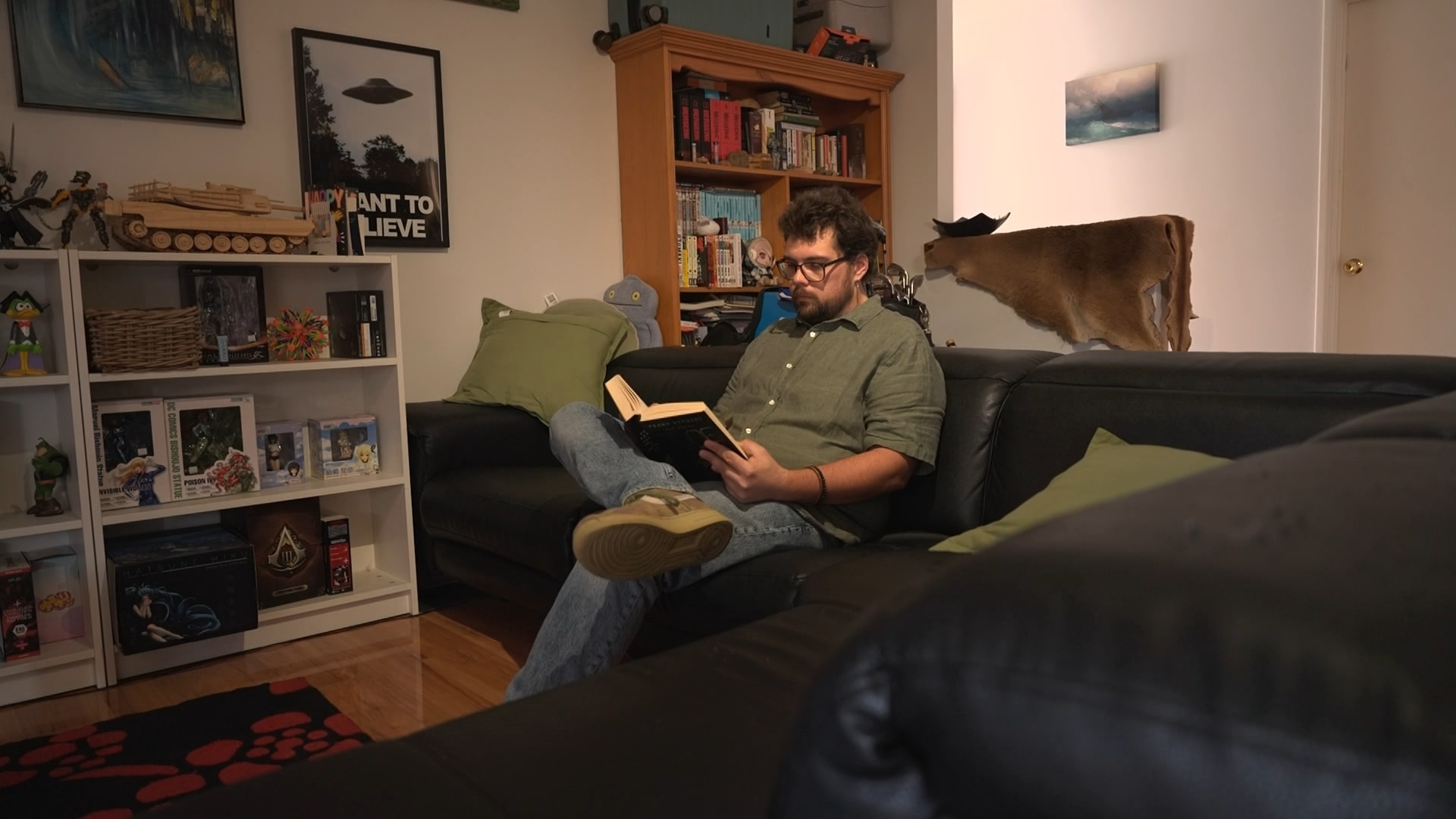 A man sits on a couch reading a book.