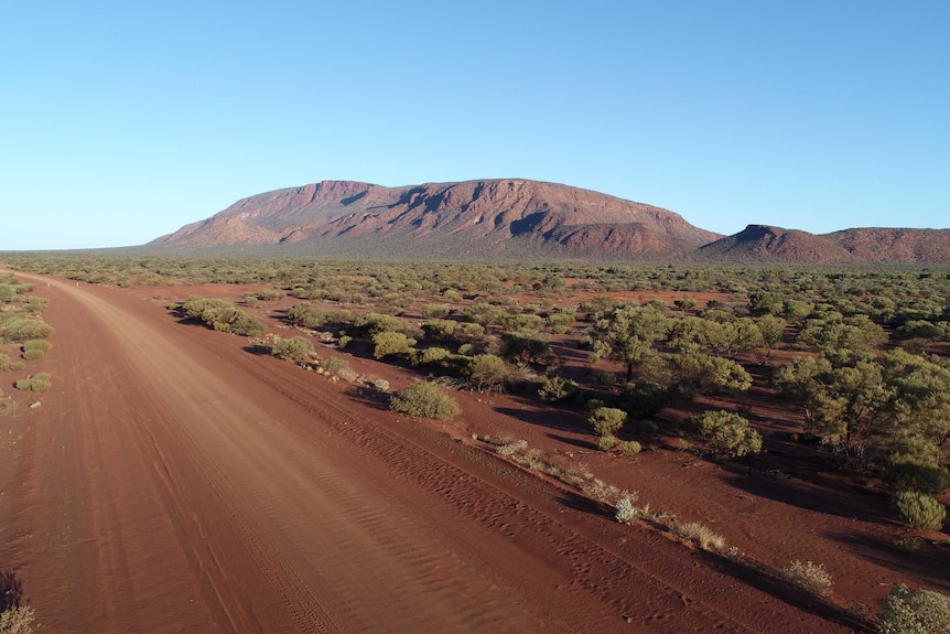 A long shot of a large, red mountain in the outback.