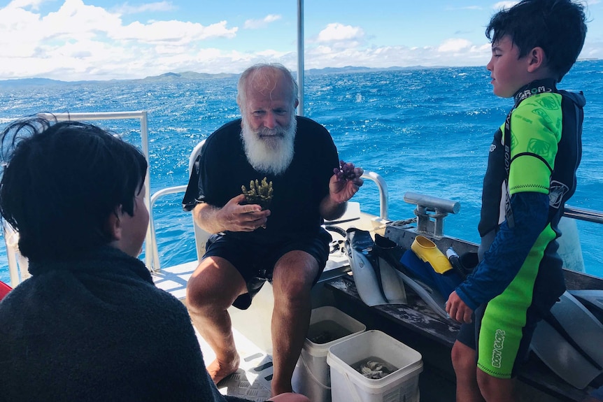 Dr Bowden-Kirby on a boat with two young tourists and the ocean stretching across the background.