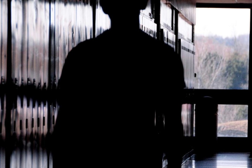 A dark silhouette of a person in an empty room.