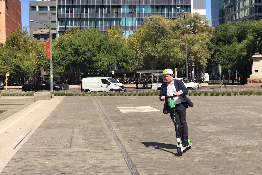 A man rides a scooter in Victoria Square.