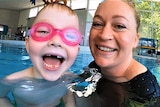Child swimming with woman