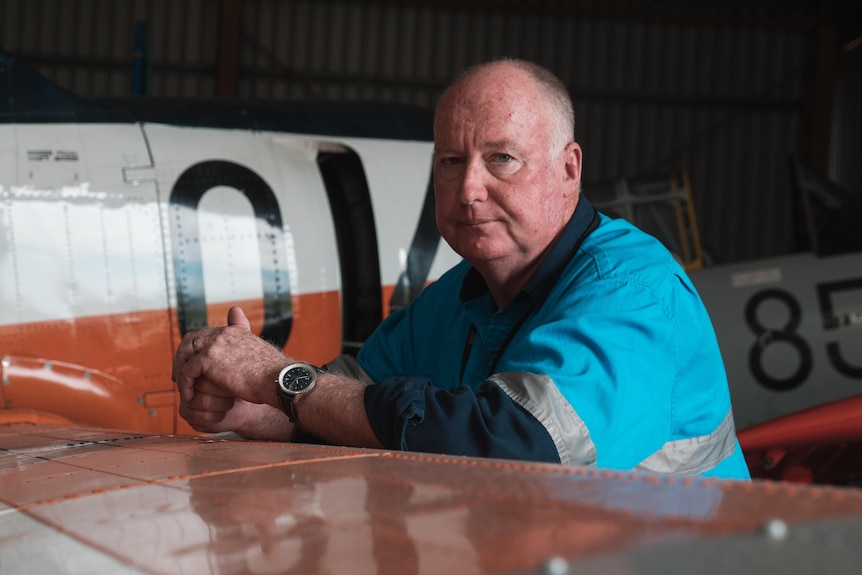 A man leans against the wing of a 1950s airforce aeroplane