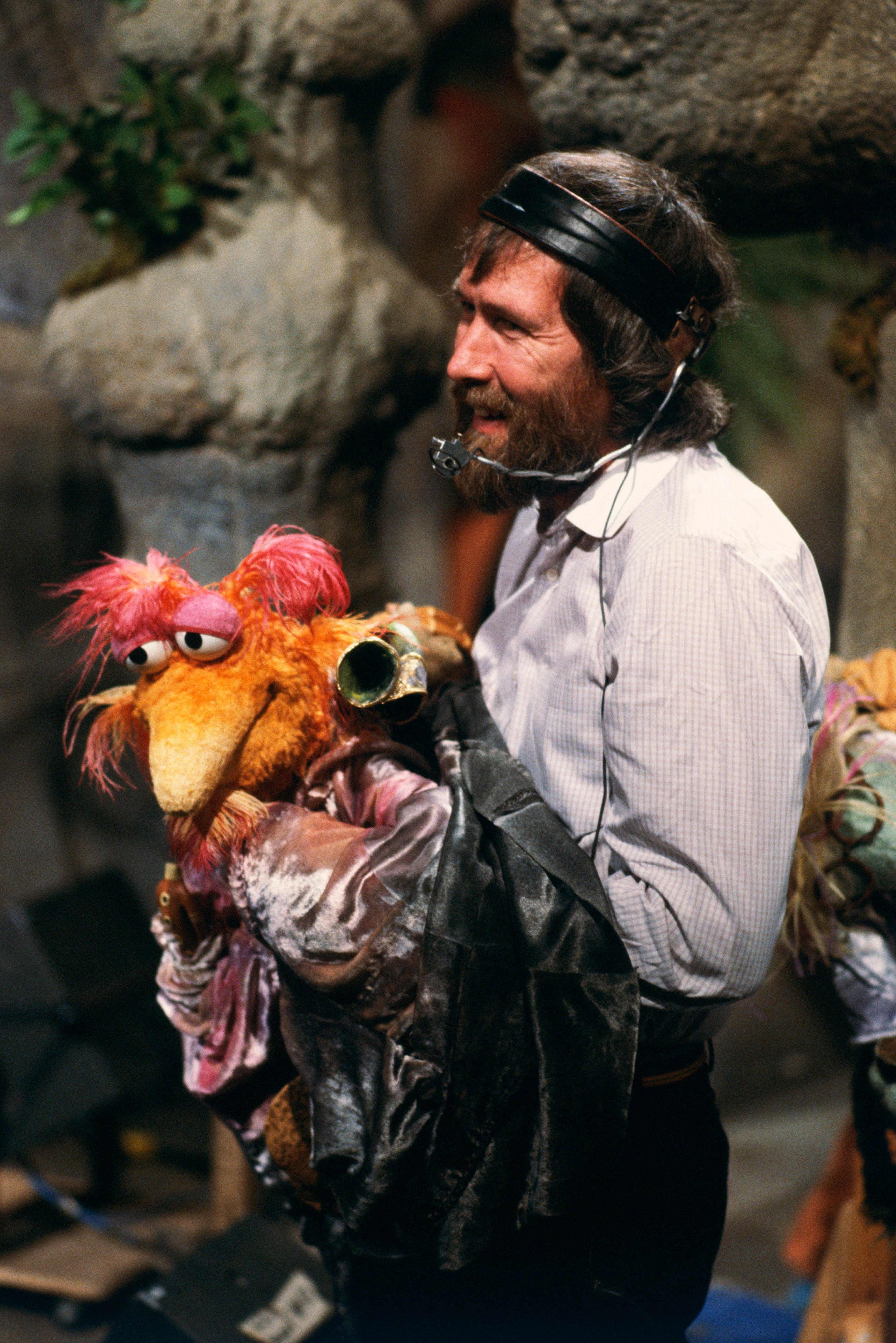 jim hneons stands holding a colourful puppet