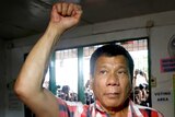 Rodrigo Duterte raises a clenched fist before casting his vote.