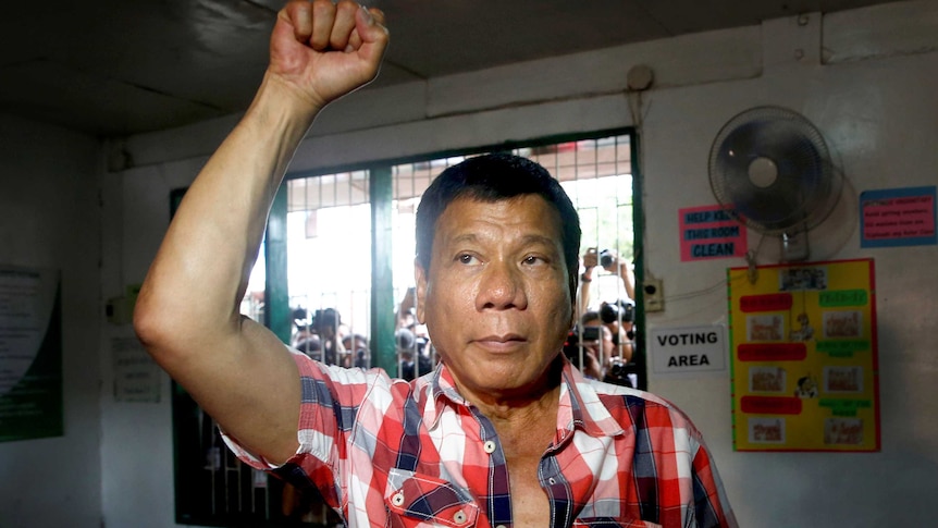 Rodrigo Duterte raises a clenched fist before casting his vote.