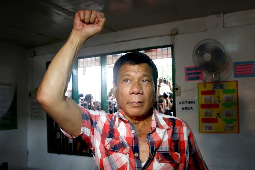 Rodrigo Duterte raises a clenched fist before casting his vote.