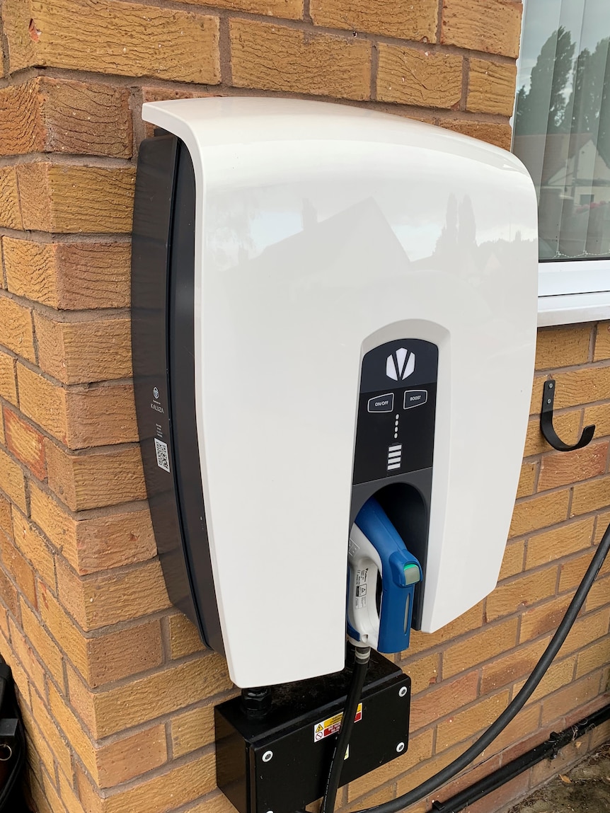 A large white box with EV charging plug installed on a brick wall