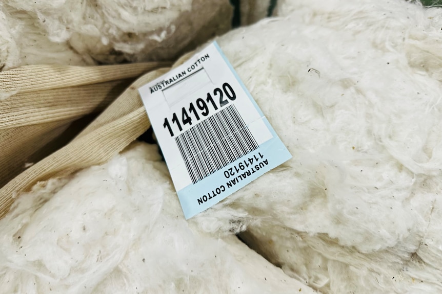 Close up photo of a label that says Australian Cotton with a barcode underneath the label is sitting on top of a bale of cotton