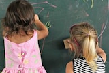 Children drawing on blackboard in classroom in rural Qld