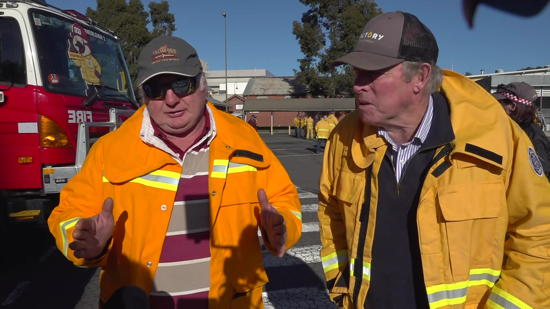two men in fire fighting outfits face camera