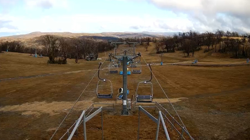 A chairlift on a ski slope with no snow cover and only grass.