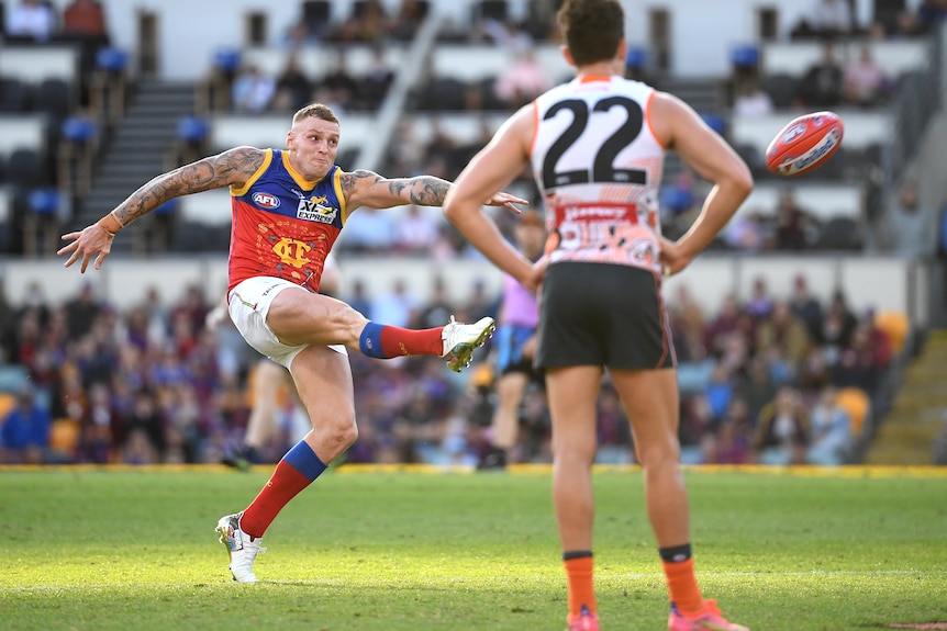 Brisbane Lions' Mitch Robinson kicks for goal as number 22 for the GWS Giants watches on in their AFL game.