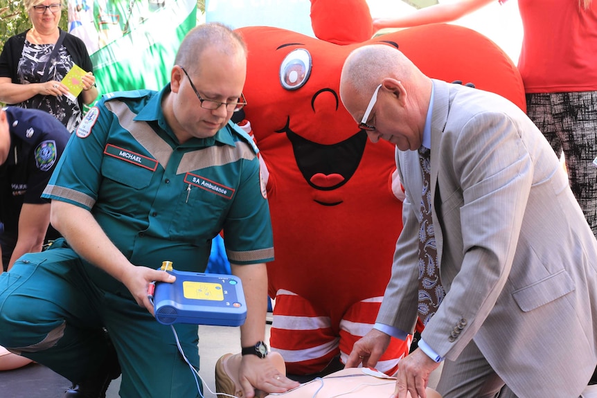 An ambulance worker and councillor Phil Martin demonstrate the new defibrillator.