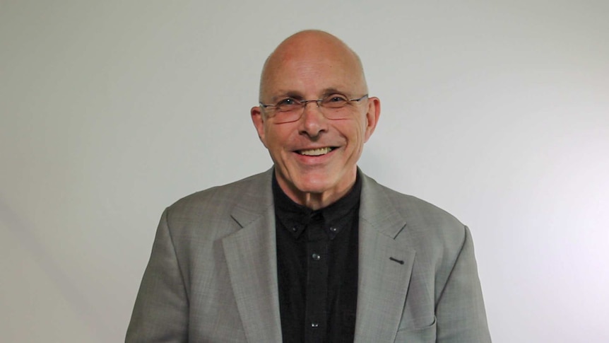 A photograph of composer Nigel Westlake wearing a grey jacket and black shirt.