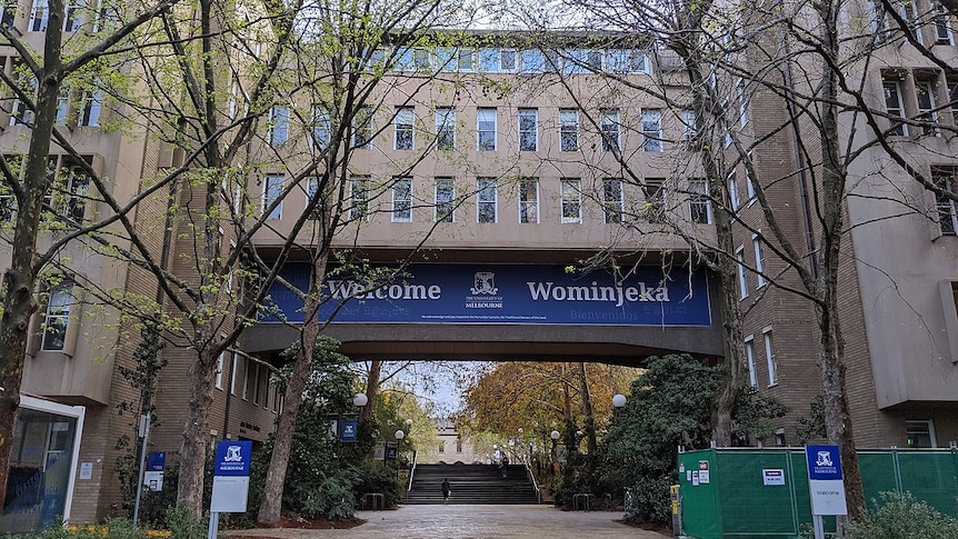 Part of the University of Melbourne campus. There are a lot of trees, and there is a blue welcome sign.