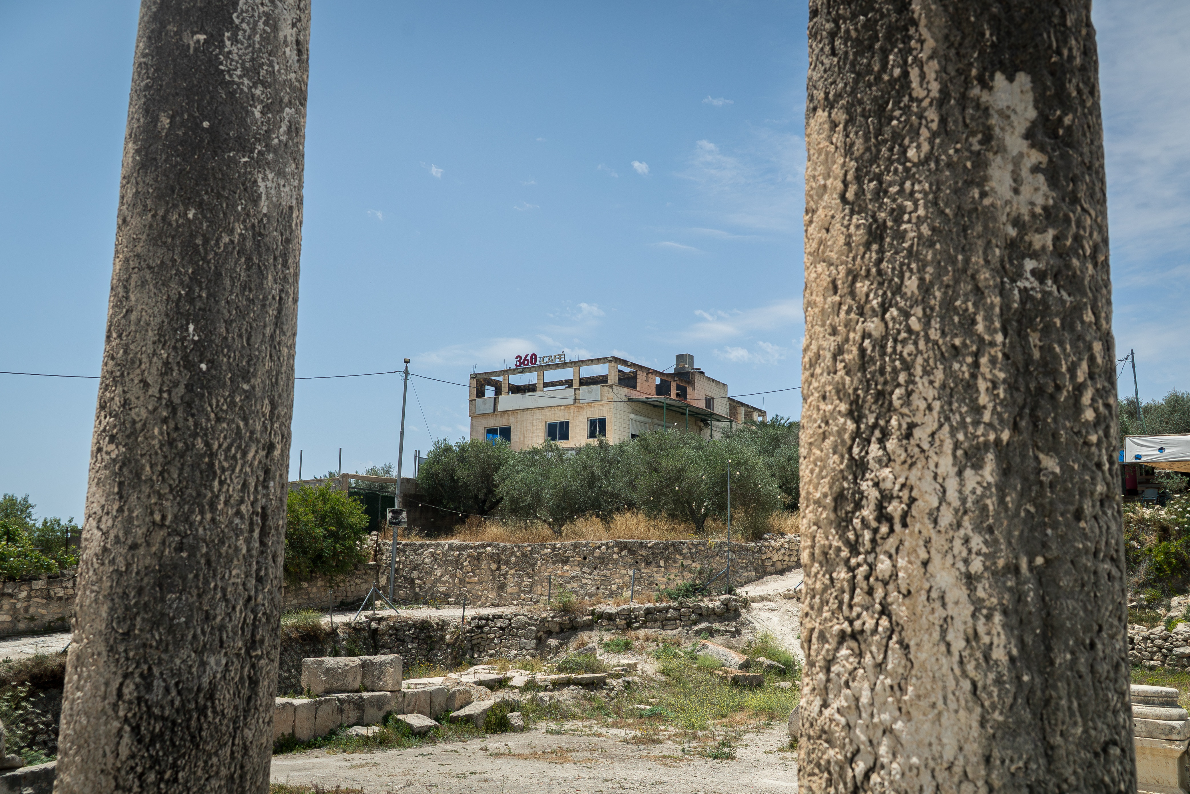 A brick building built on a hill overlooking a site covered in ancient Roman ruins.