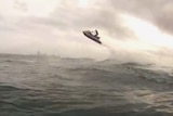 Jet ski flying into the air off the back of a wave